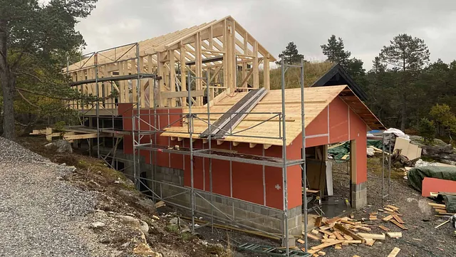 Et hus under oppføring, med et reisverk og rød isolasjon i veggene.