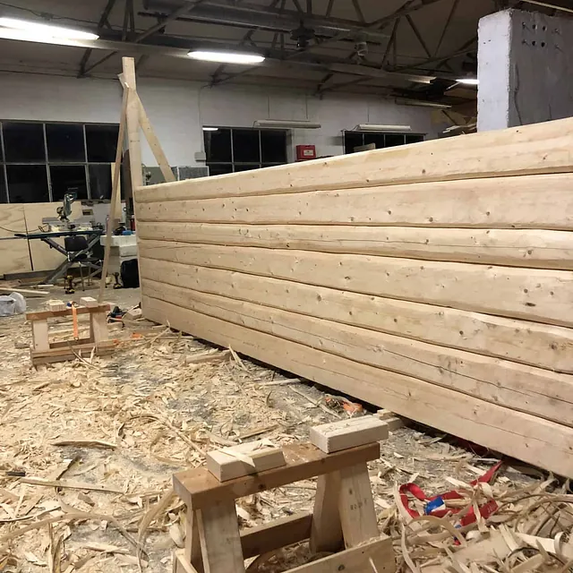 En nylaget tømmervegg med spon og trefliser på gulvet.