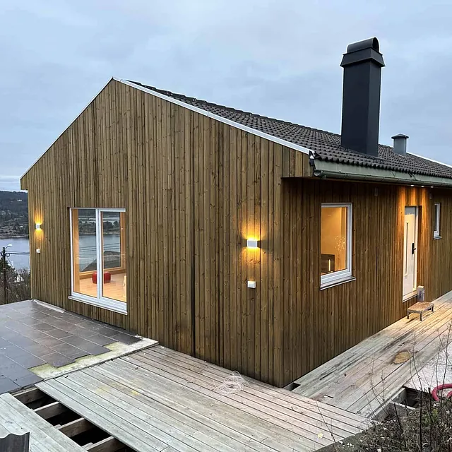 Hus i treverk under bygging med utsikt over vannet.