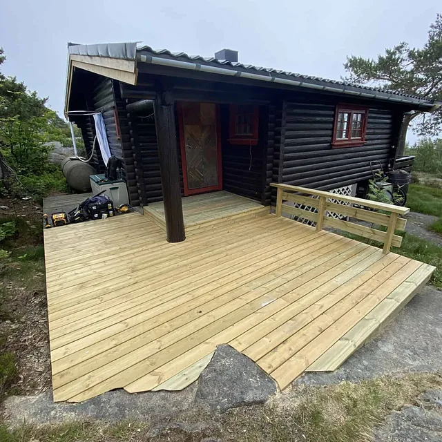 En hytte med nybygd platting foran.