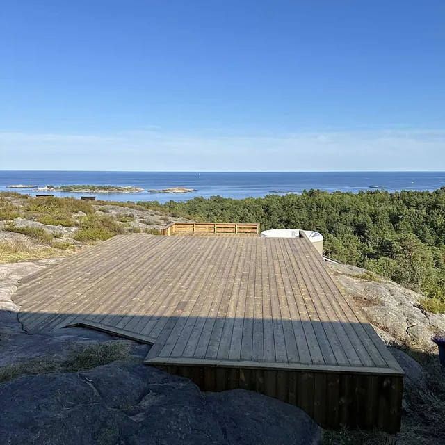 Stor treplatting med boblebad og utsikt over et hav.