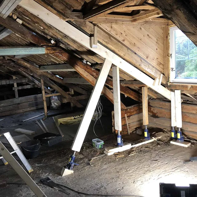 Loft som er under restaurering, med nye bjelker, vinduer og jekker som holder konstruksjonen.