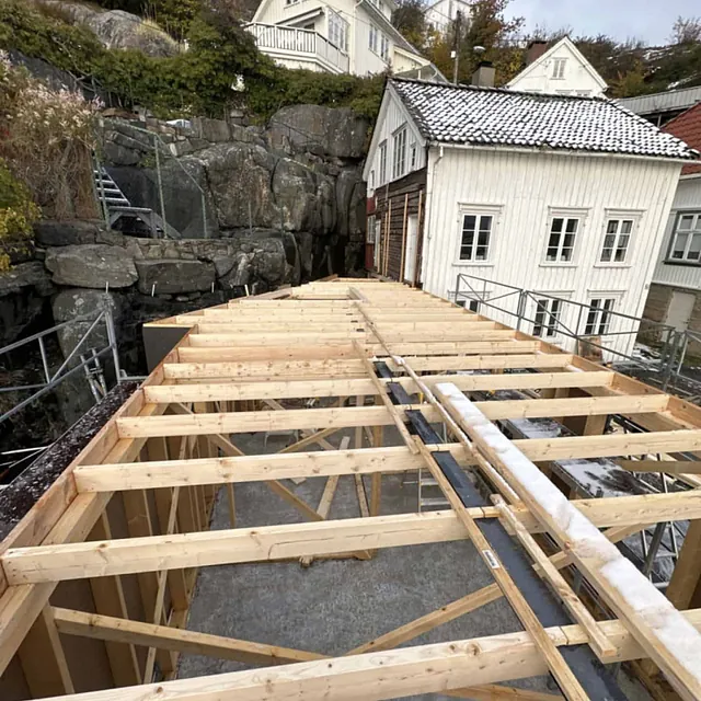 Et nytt tak under bygging mellom to eldre hus i et nabolag.